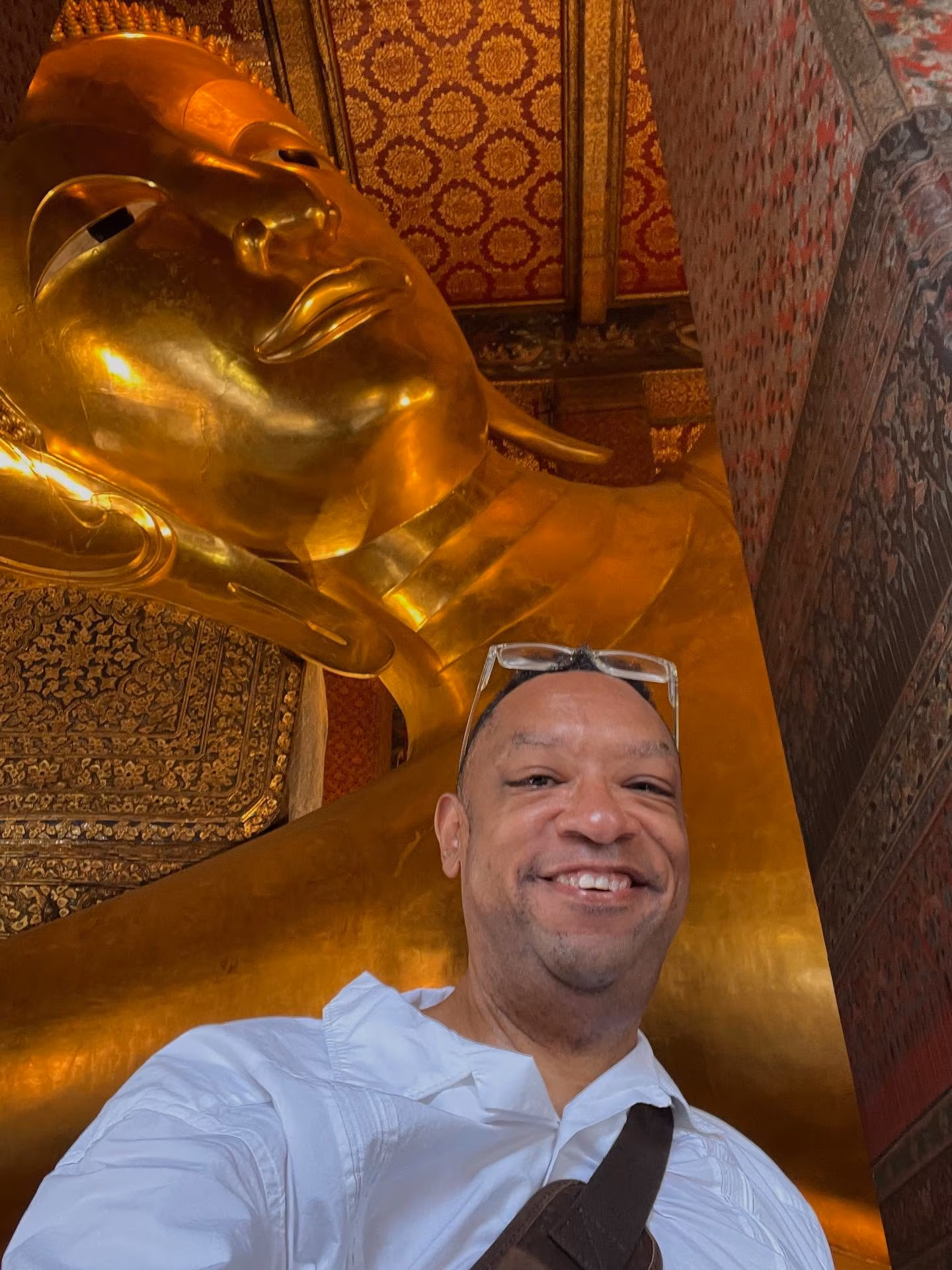 Reggie Hayes paused in gratitude at Wat Pho’s reclining Buddha during a quiet Thai sunrise